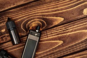 Nicotine salt vape device and e-liquid bottle on a rustic wooden table, offering a smooth vaping experience