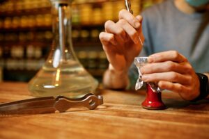 A person carefully punctures foil on a hookah bowl with tools, symbolising the precision needed to dilute nicotine salts and customise vape juice strength and flavour.