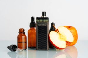 Disposable vape device with apple and vape juice bottles, showcasing fruity vape flavours.